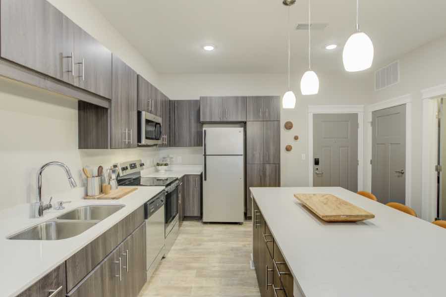 Apartment kitchen with large island, stainless appliances, and decorative lighting